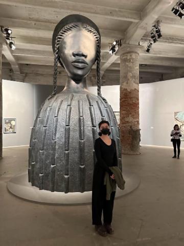 Two people standing in an art museum near a large sculpture.