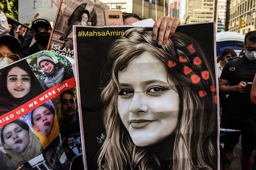Protest with large portrait photo and diverse crowd holding signs.