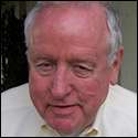 Older man smiling, wearing a light-colored shirt outdoors. image link to story