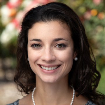 A woman smiling in front of a floral background. 