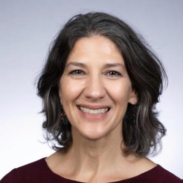 A woman smiling in a headshot with a gray background.