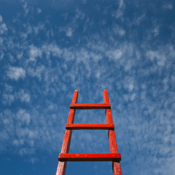 A red ladder extending up into a blue sky. 