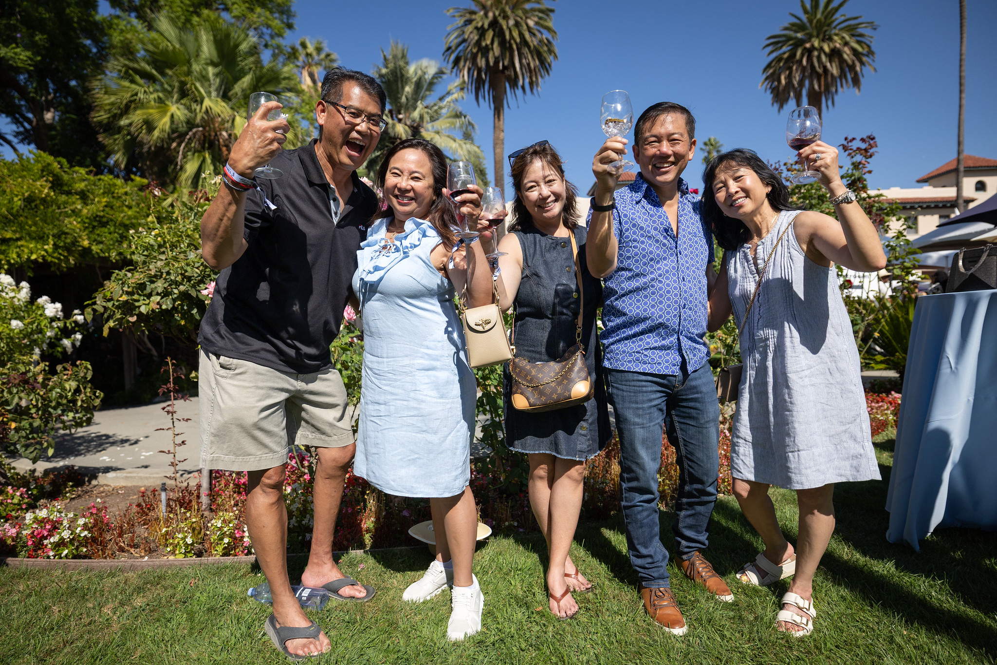 A group of alumni cheers the camera in the mission gardens 