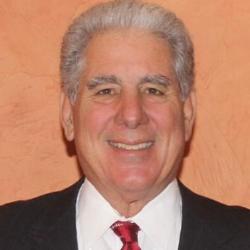 A person smiling in a suit and red tie.