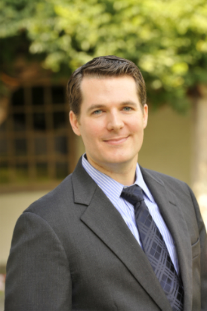 A man in a suit and tie standing outdoors. image link to story